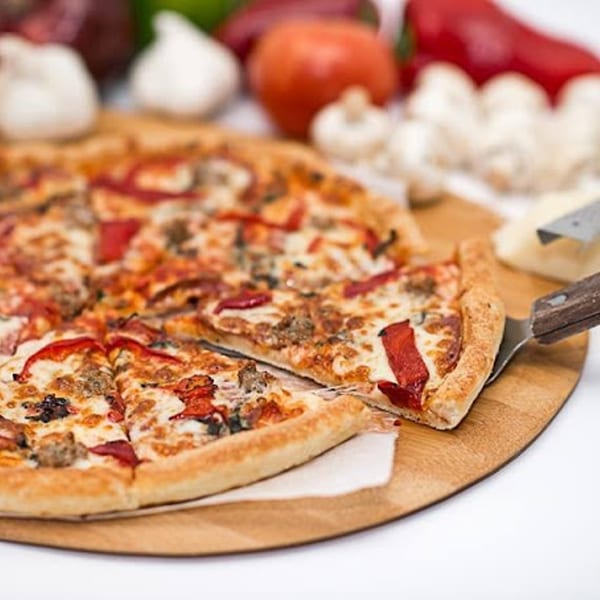 A Soprano's Pizza and Pasta pizza with red peppers and sausage, with a slice being served.